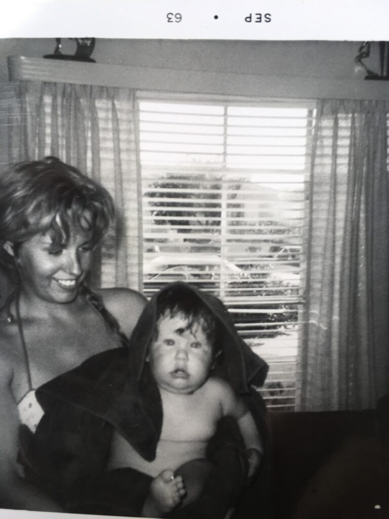 Smiling woman holding towel-wrapped baby by window