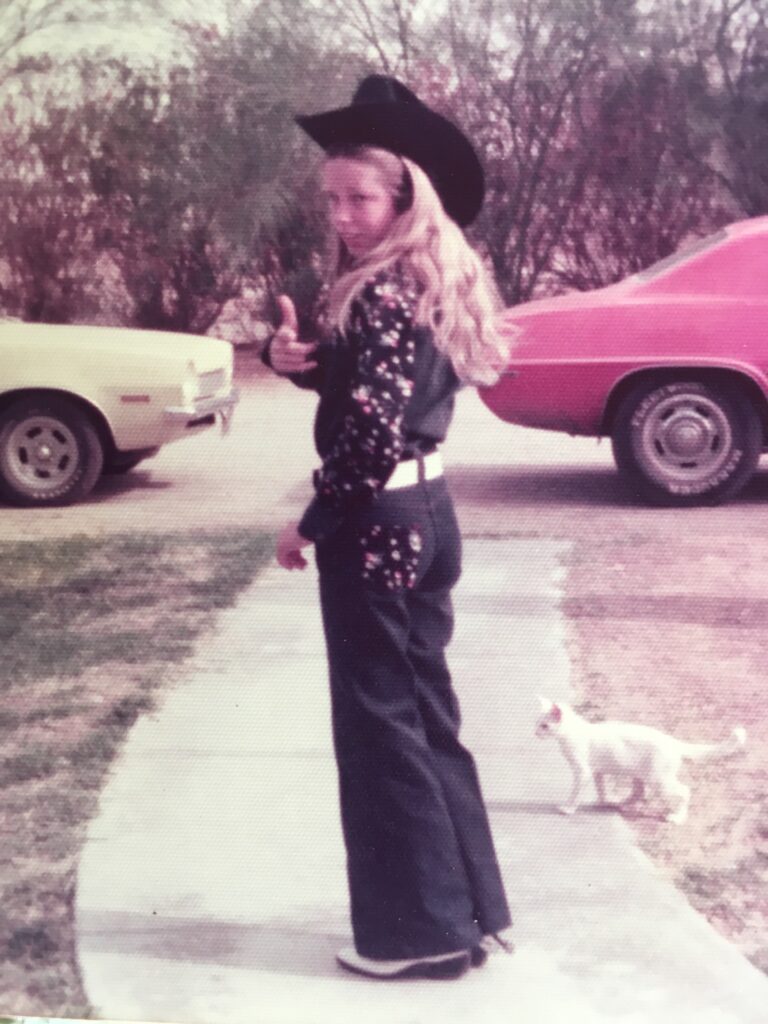 Girl in cowboy hat pointing, white cat nearby