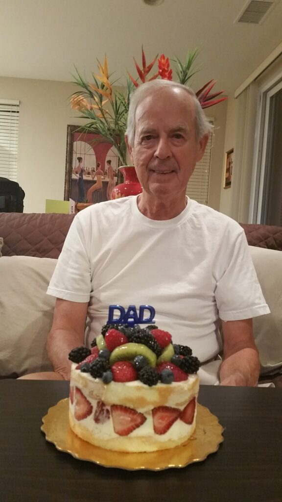 Older man smiling with fruit-topped cake