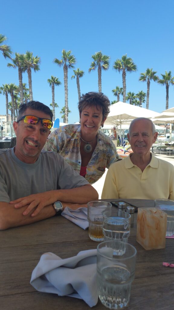 Three people smiling at sunny outdoor cafe