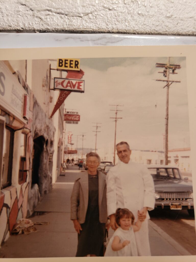 Three people on sidewalk by vintage storefront