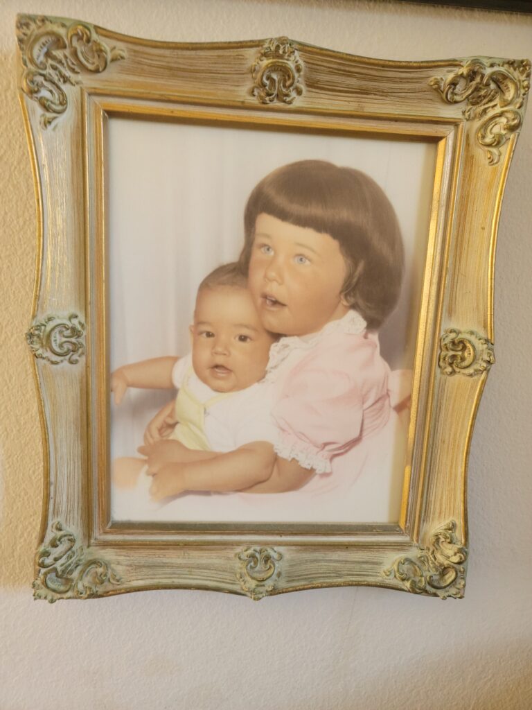 Gold-framed portrait of older child holding baby