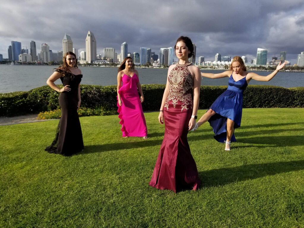 Four women in evening gowns by waterfront skyline
