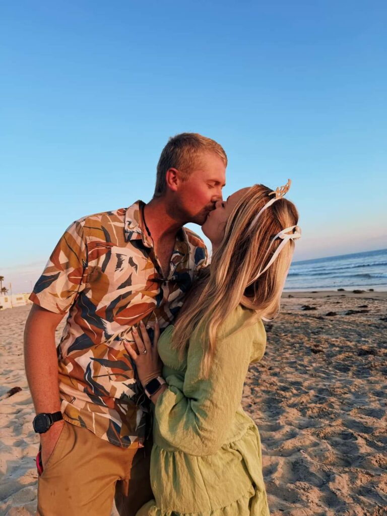 Couple kissing on sandy beach at sunset