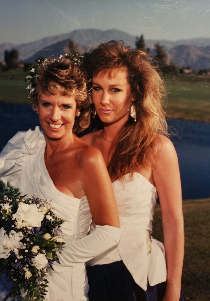 Two women in white dresses holding bouquet