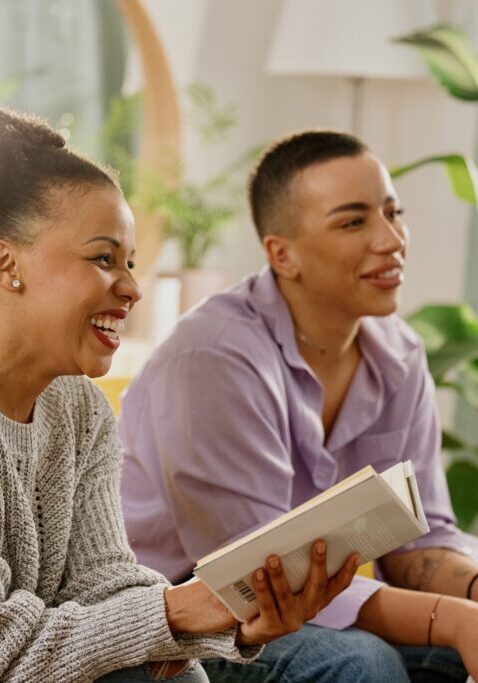 Two people smiling and holding books indoors.
