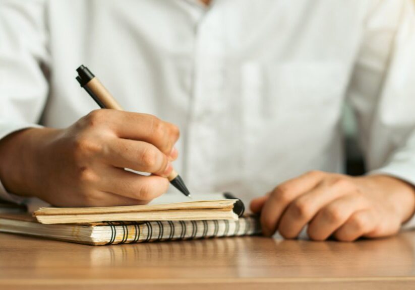 businessman working at work table,home office desk background, checklist writing planning investigate enthusiastic concept. Male hand taking notes on the notepad.