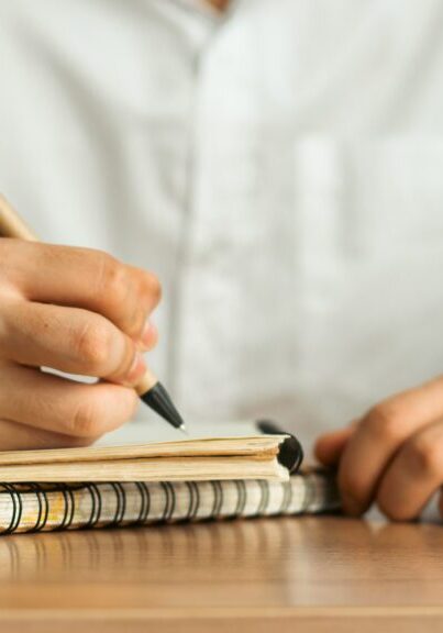 Hands writing in spiral notebook with pen