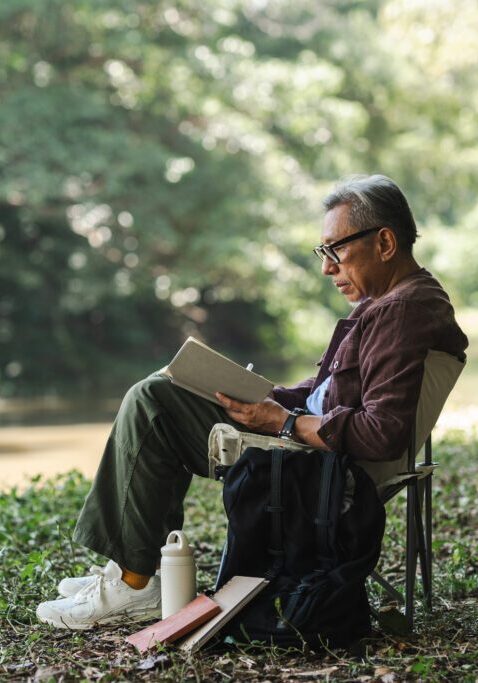 Man reading by a riverside in nature.