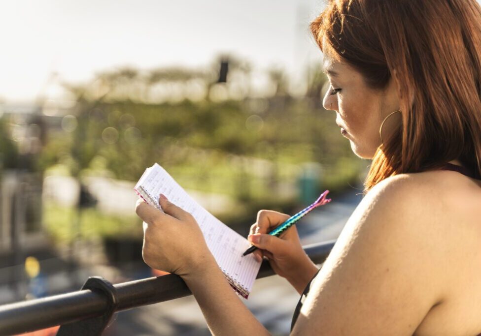 Woman writing in notebook outdoors.