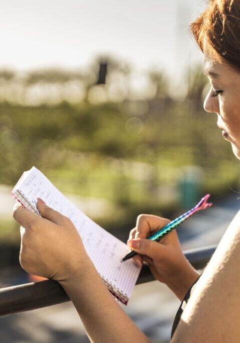 Woman writing in notebook outdoors.