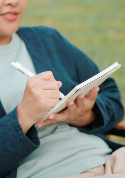 Person writing in notebook outdoors